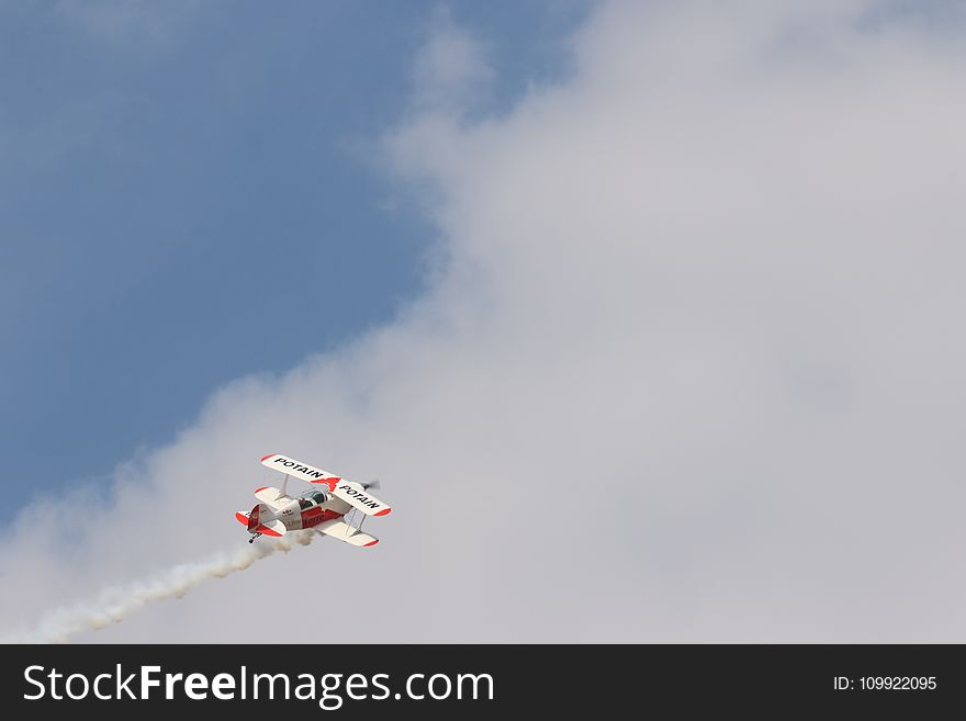 White and Red Biplane Flying during White Cloudy Day