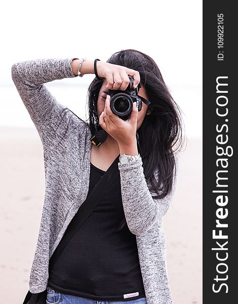 Woman in Gray Cardigan and Black Shirt Holding Black Dslr Camera