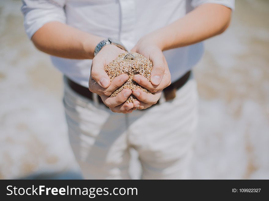 Shallow Focus Photography of Person Holding Brown Sand