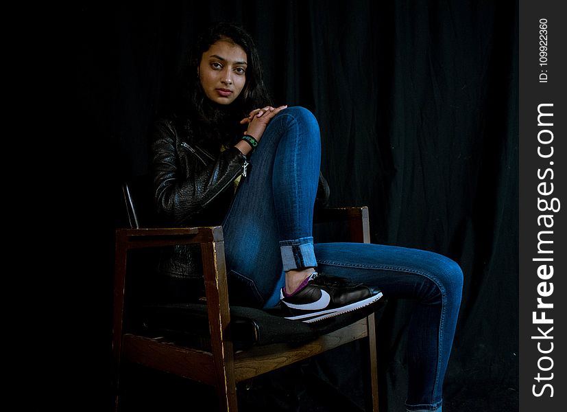 Woman Wearing Blue Jeans Sitting on Brown Wooden Armchair