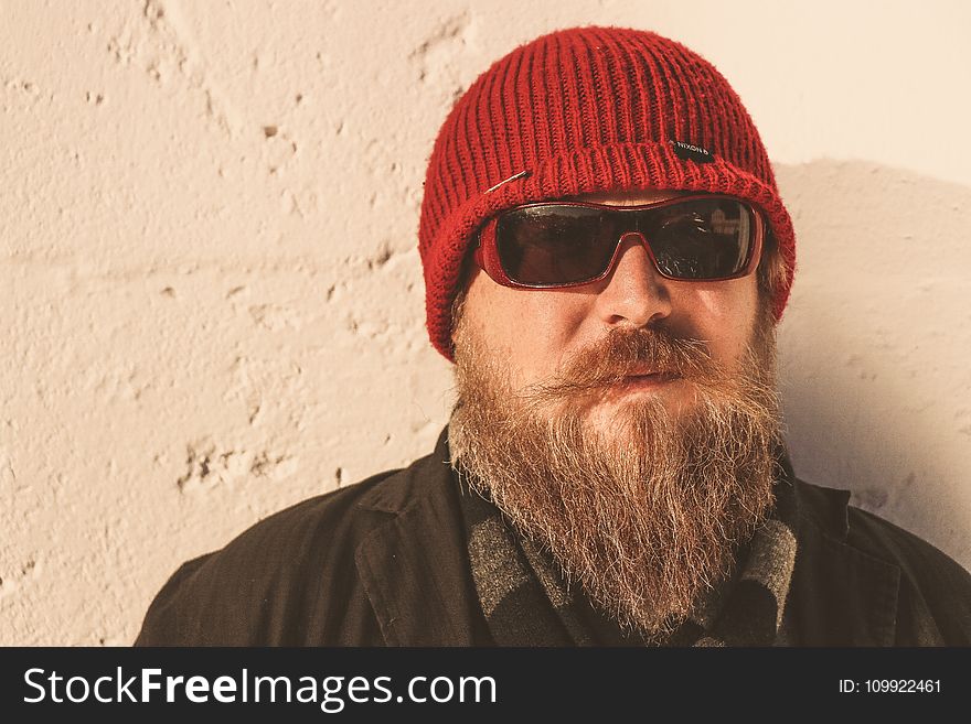 Bearded Man Wearing Red Beanie Cap, Sunglasses ,and Black Jacket