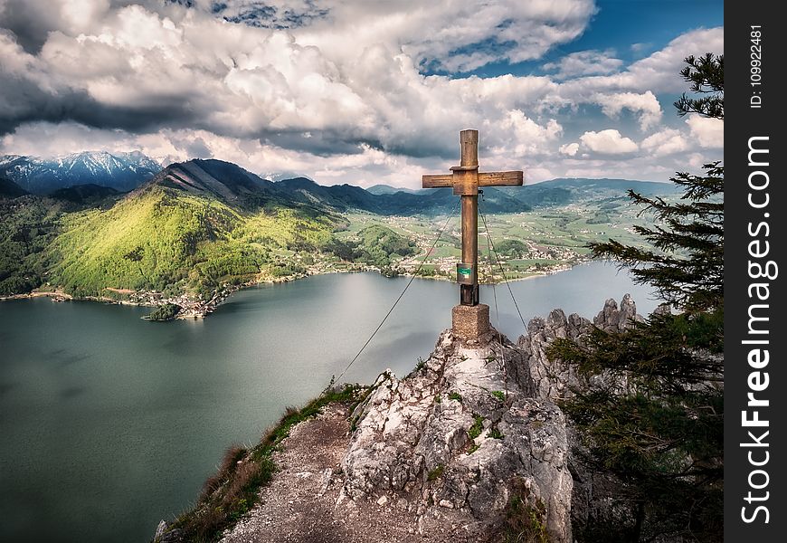 Brown Cross Near Body Of Water Under White Sky