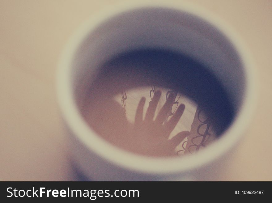 Silhouette Of Hand In White Ceramic Cup