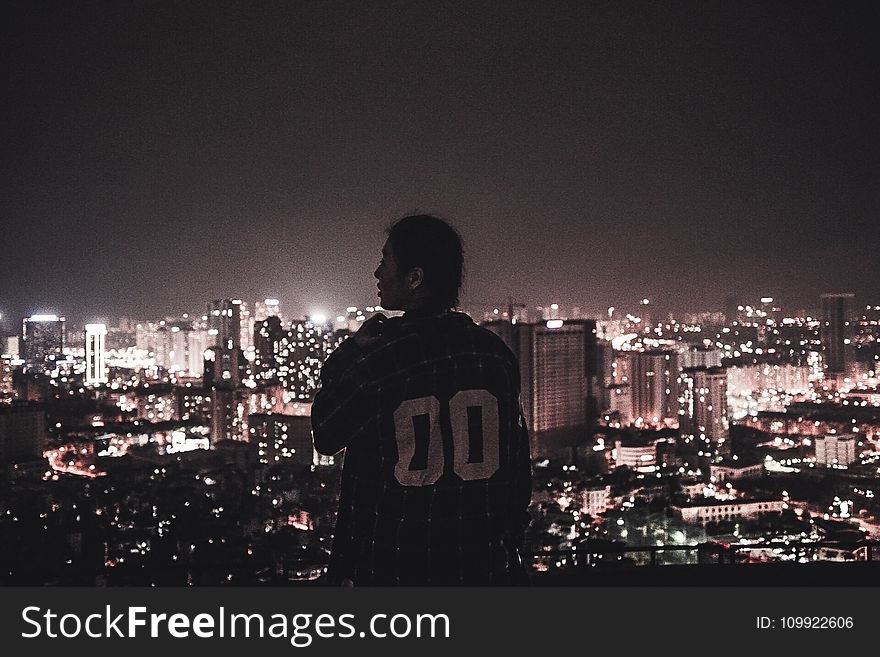 Photography Of A Person Watching Over City Lights During Night Time