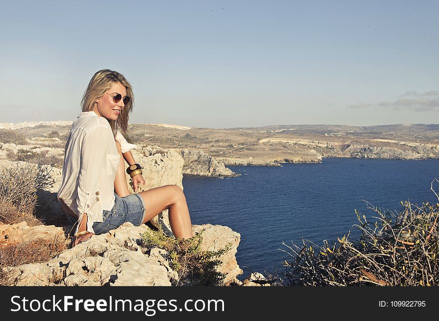 Photo of a Woman Sitting on the Cliff
