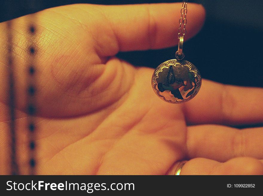 Person Holding Round Silver-colored Necklace Pendant
