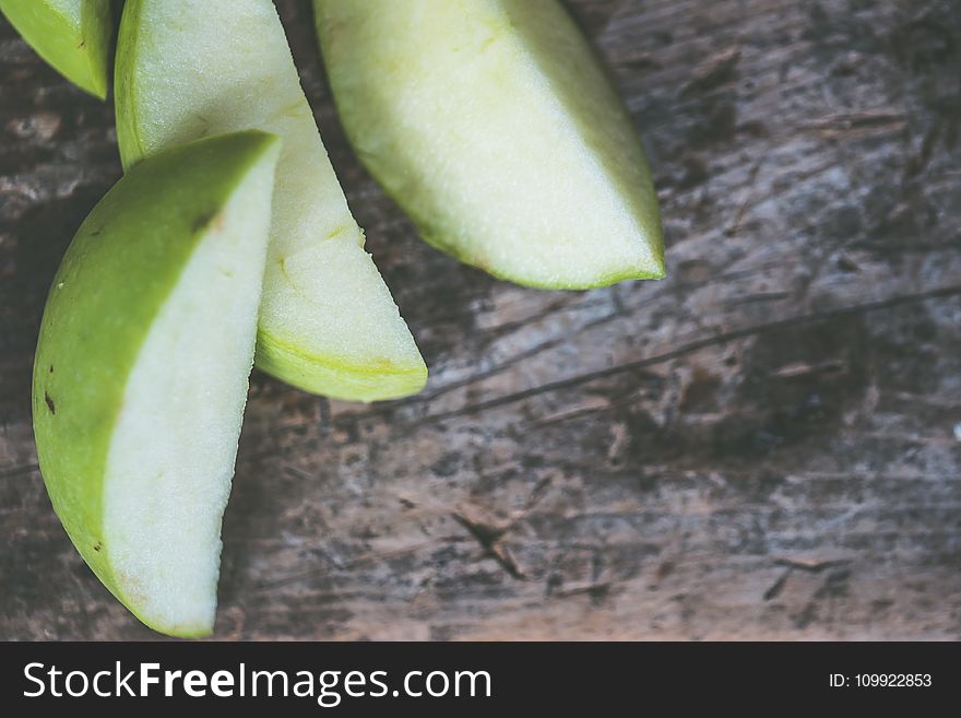 Close-Up Photography of Sliced Green Fruit on Brown Wooden Surface