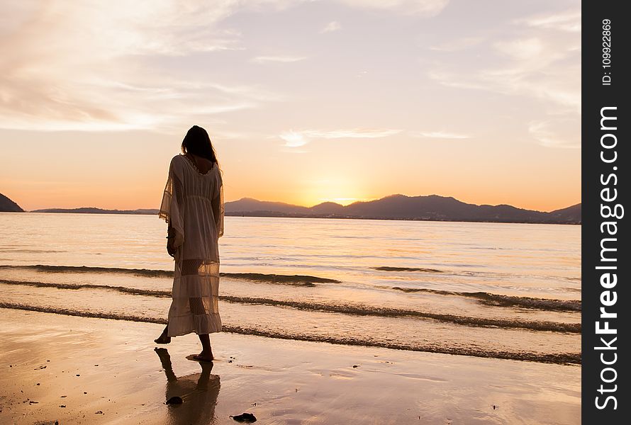 Woman iIn White Dress Walking On Beach