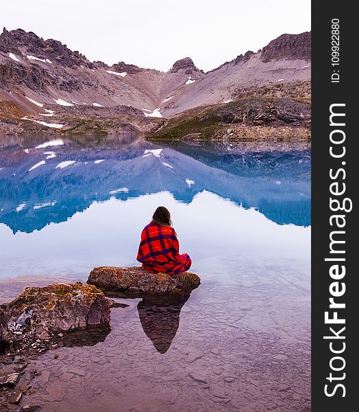 Person Sitting On Rock By The Lake