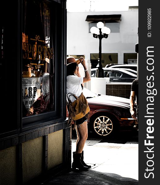 Woman in Brown Sunhat Standing on Sidewalk