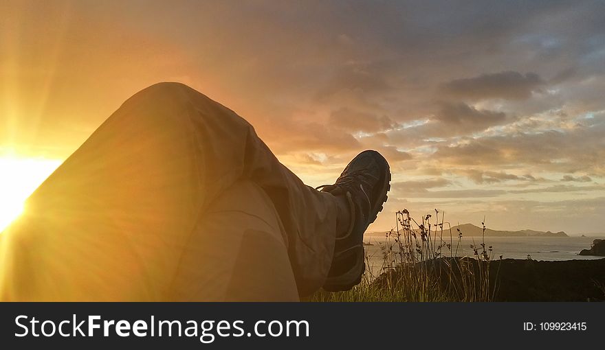 Sun Reflecting on Person Cross Leg Under Cumulus Clouds during Sunrise