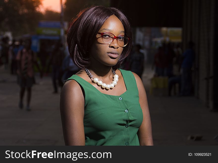 Woman In Green Sleeveless Dress With White Beaded Necklace And Red Framed Sunglasses