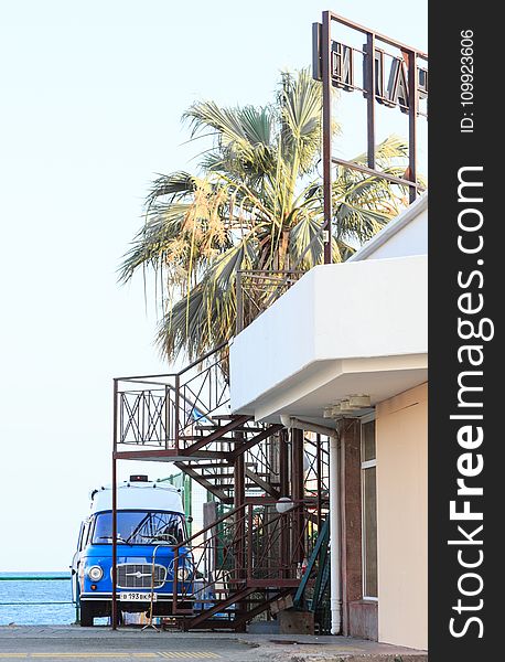 Blue Vehicle Park Near Brown Metal Outdoor Stairs And White Concrete House At Daytime