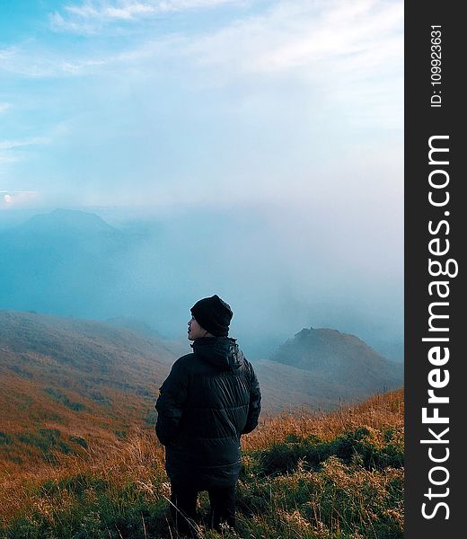 Man in Black Jacket Standing on Mountain With Fog