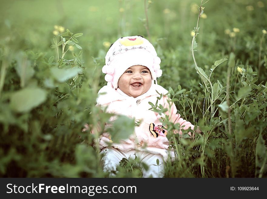 Toddler Wearing Whit Cap On Green Field