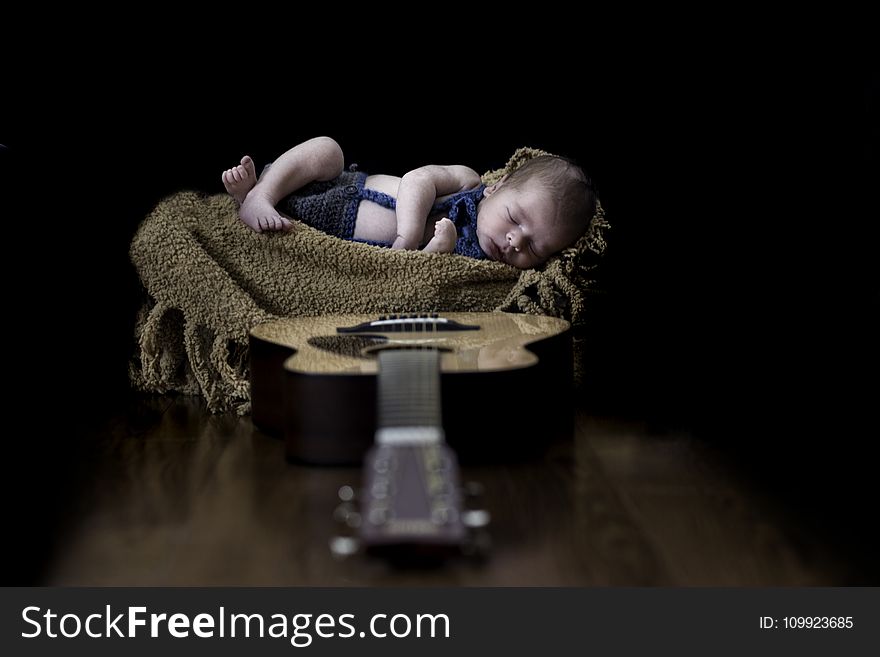Baby on Beige Textile Near Brown Dreadnought Acoustic Guitar