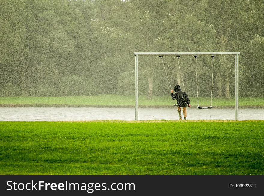 Person In Black Hoodie Riding Swing While Raining