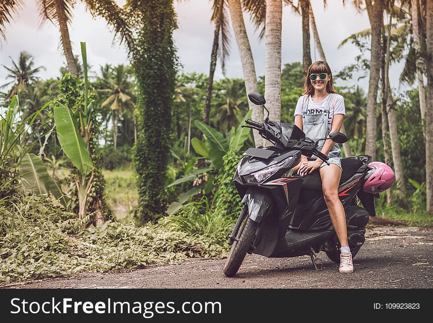 Woman in Gray Shirt Riding Black Motor Scooter