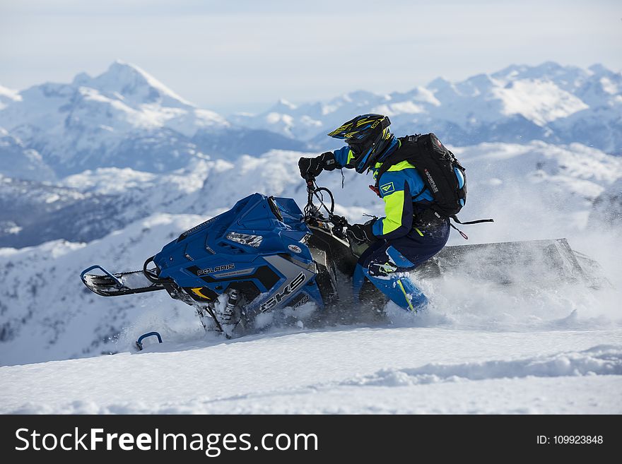 Man In Blue And Green Long-sleeved Suit Riding On Snowmobile