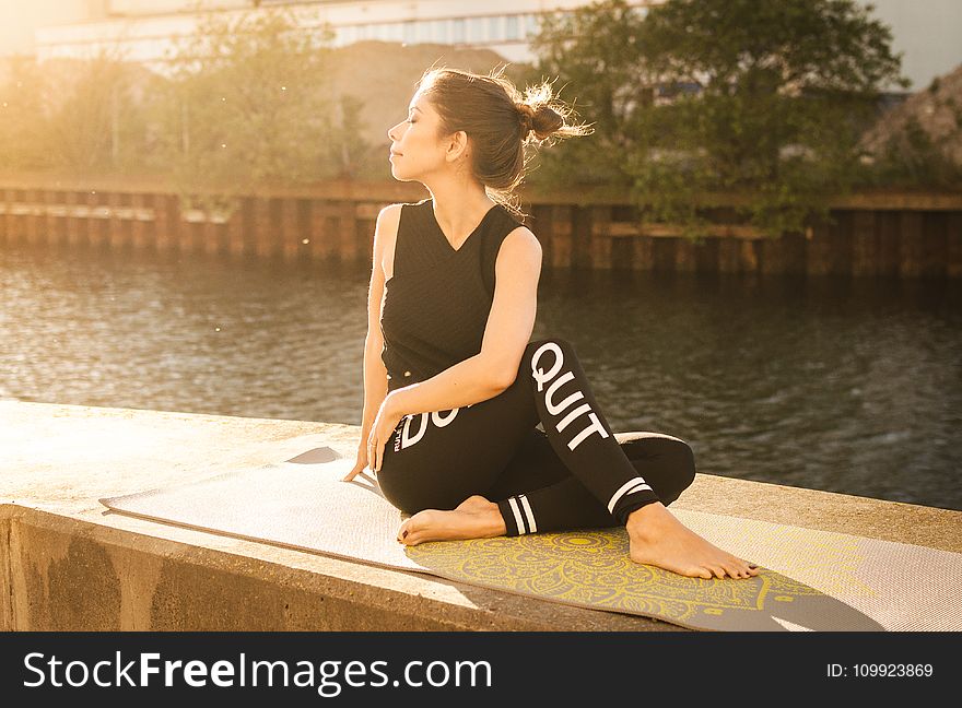 Woman Wearing Black Fitness Outfit Performs Yoga Near Body of Water