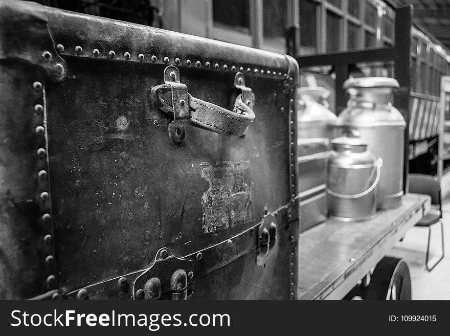 Grayscale Photography of Travel Case With Milk Churns on Trailer