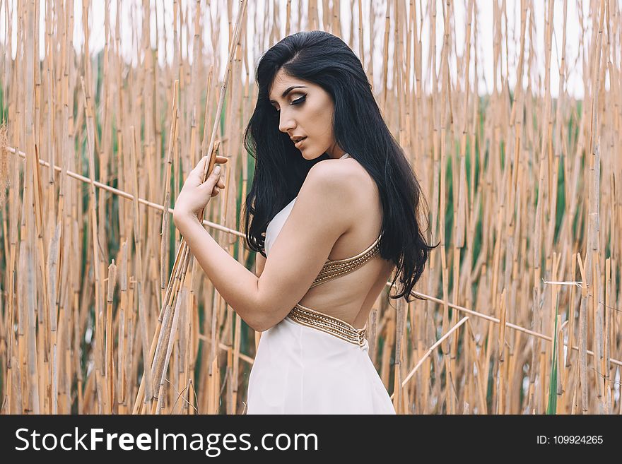 Woman In White Backless Dress In Front Of Bamboo Sticks