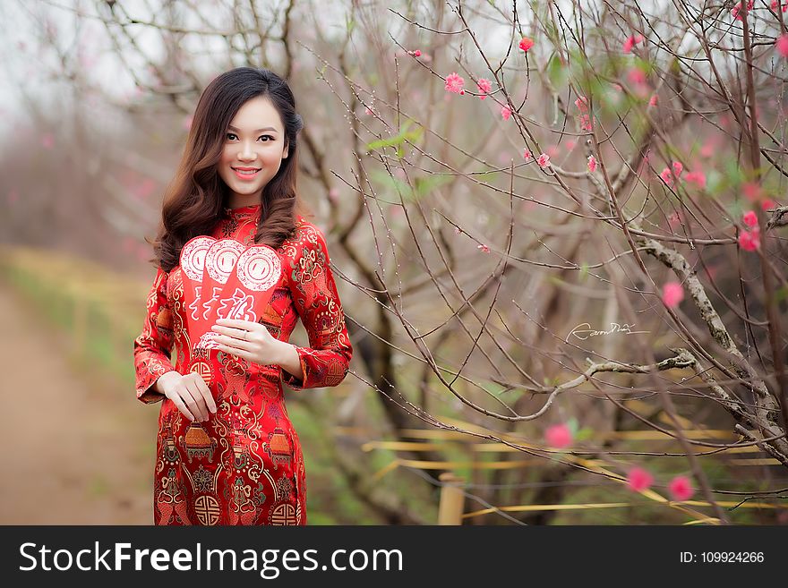 Woman in Black and Red Floral Long-sleeved Shirt Stands Near Green Plant