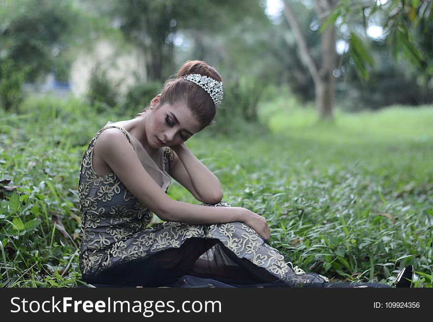 Woman Wearing Brown and White Sleeveless Floral Embroidered Dress Sitting on Green Grass Field
