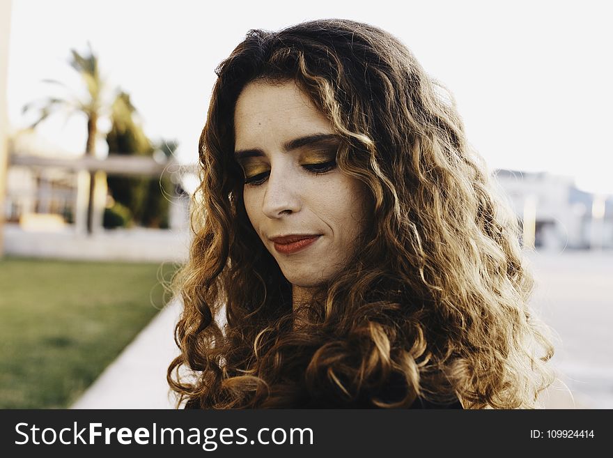 Curly Brown Haired Woman Wearing Black Shirt With Red Lipstick Looking Down