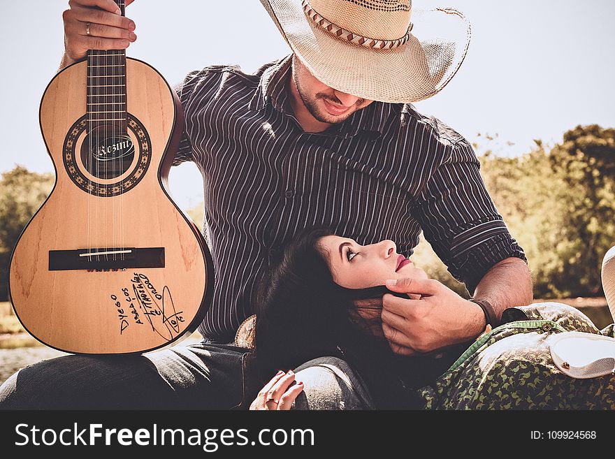 Woman In Green Top With Man In Black Long-sleeved Shirt Holding Autographed Brown Guitar