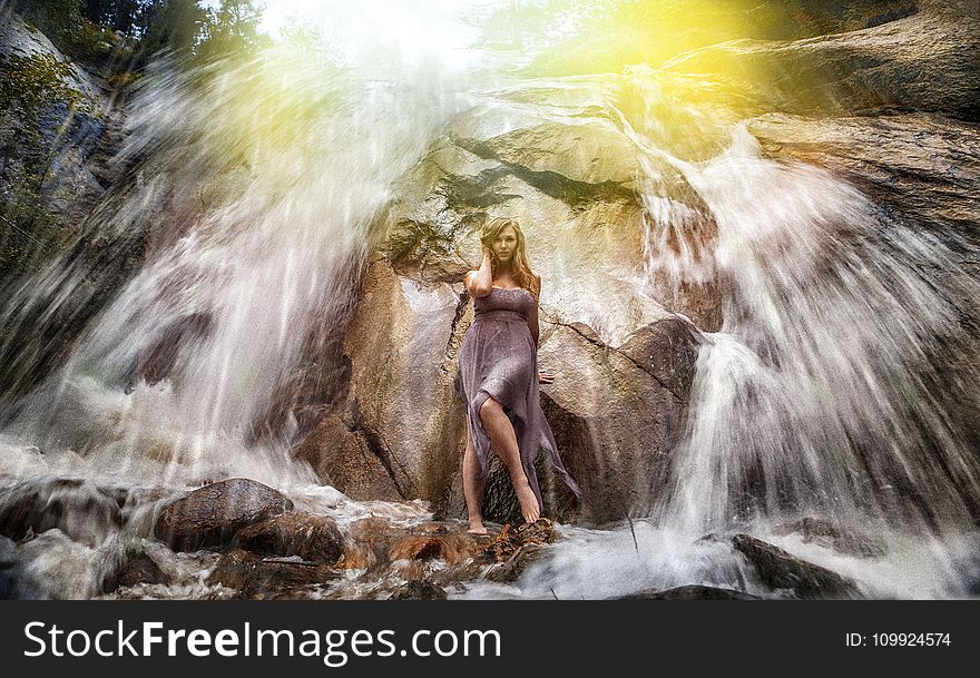 Woman in Gray Strapless Long Dress Standing Under Waterfalls