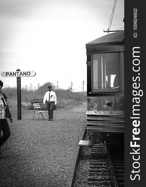 Grayscale Photo of Man Walking Near Train