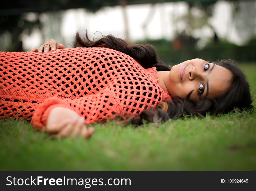 Photo Woman in Orange Long-sleeved Shirt Laying on Lawn
