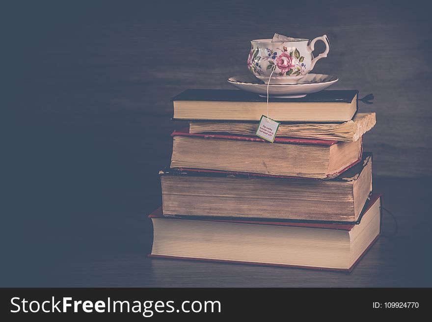 Pile Of Hardbound Books With White And Pink Floral Ceramic Teacup And Saucer