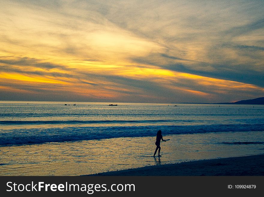 Photo of Person Walking on Beach Shore