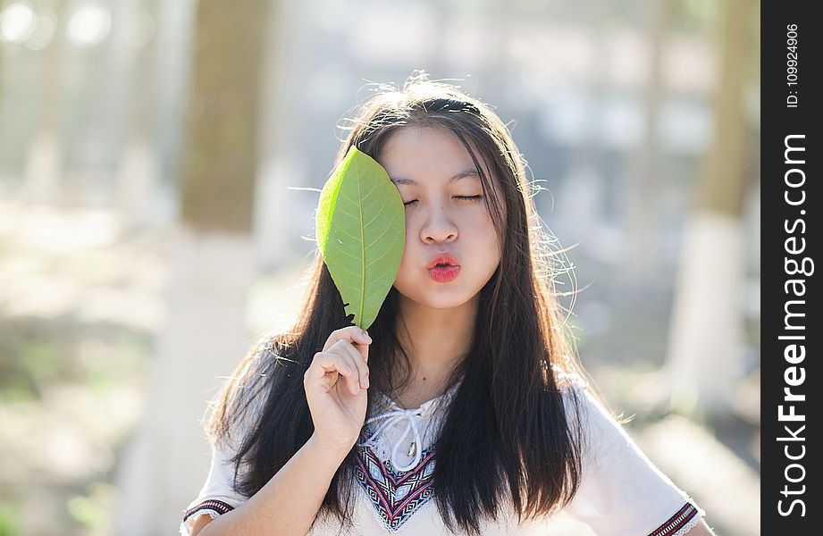 Woman Holding Green Leaf With Lips Kissing And Closing Eyes