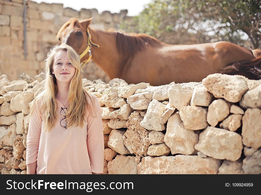 Woman Wearing Pink V-neck 3/4 Sleeved Shirt With Eyeglasses Standing in Front of Brown Horse