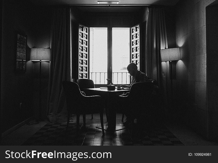 Silhouette Photography Of Man Sitting On Chair Beside Open Window