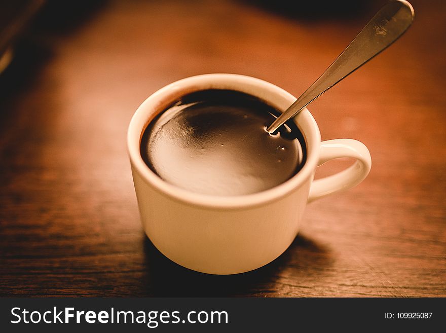 White Ceramic Espresso Cup Filled With Coffee On Brown Wooden Surface