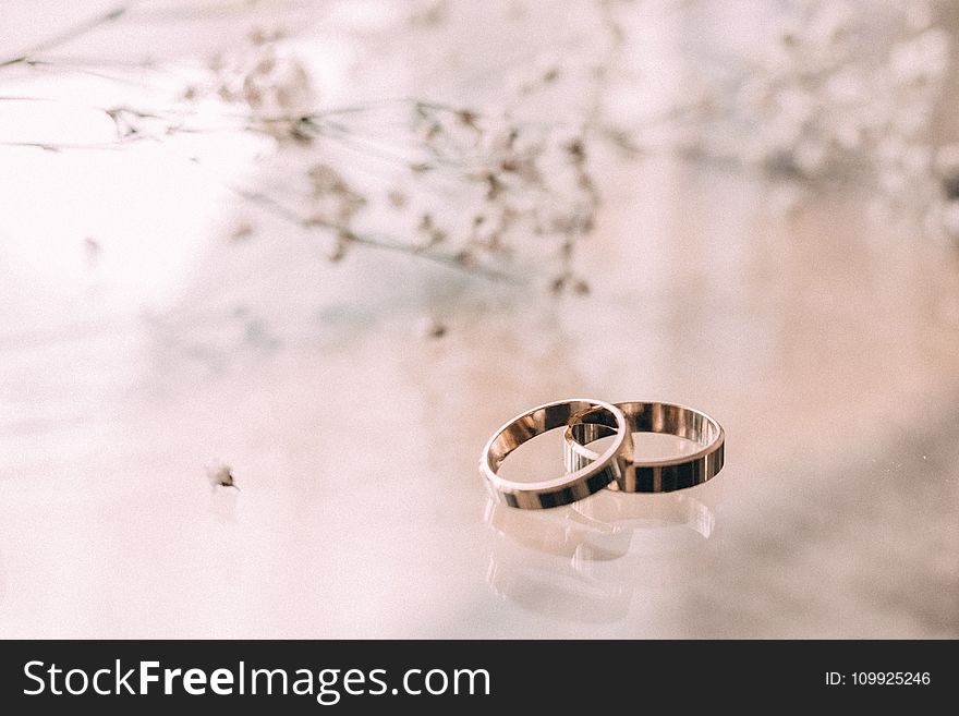 Two Silver-colored Rings on Beige Surface