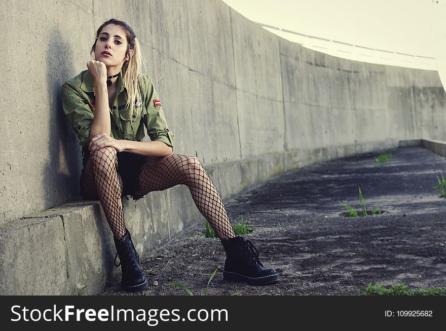 Woman Sits Besides Gray Concrete Wall
