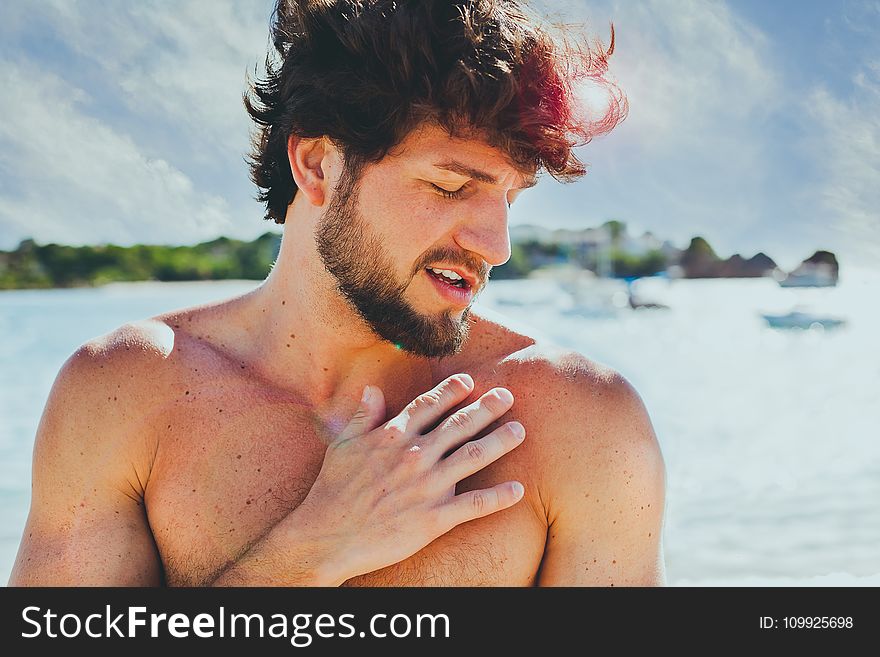 Topless Man In Front Of Body Of Water