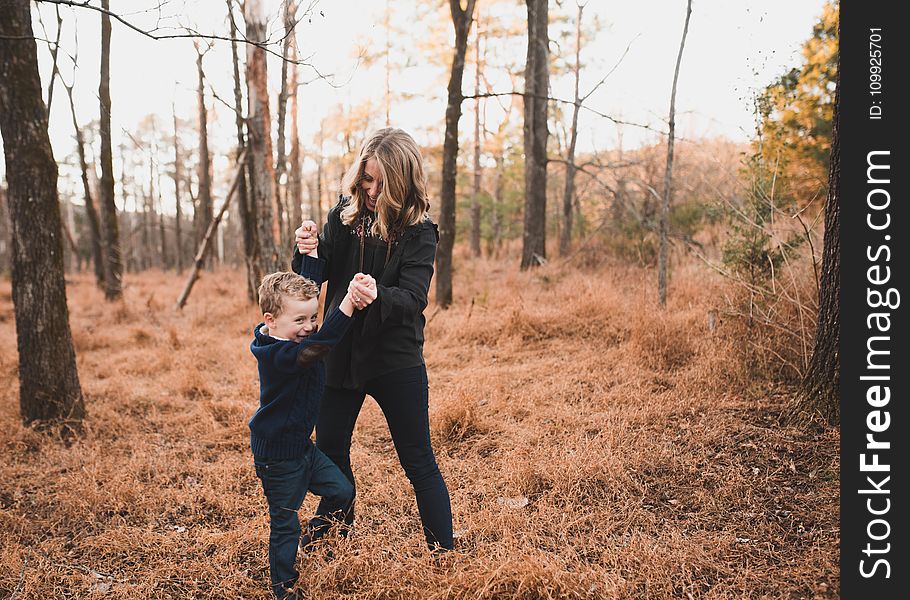 Woman Wearing Black Jacket Playing With Young Boy
