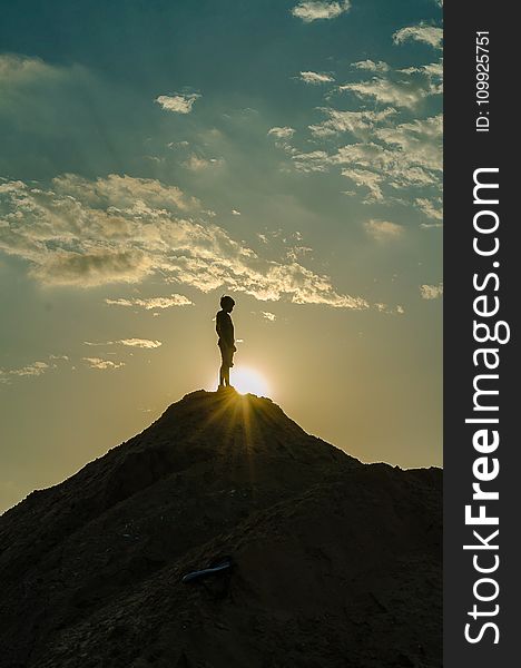 Silhouette of a Man Standing on a Mountain
