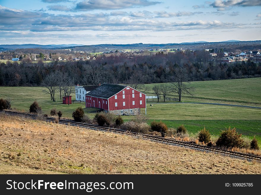 Red And Grey House In The Middle Of Green Grass Field