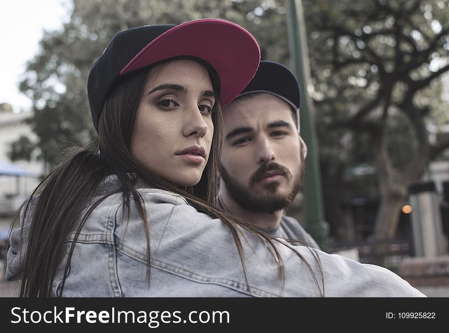 Woman In Blue Denim Jacket Near Man In Black Cap