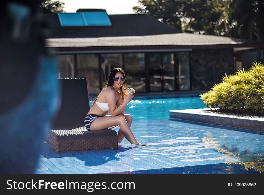 Selective Focus Photography of Woman Wearing Black and White Bikini Sitting Brown Chair