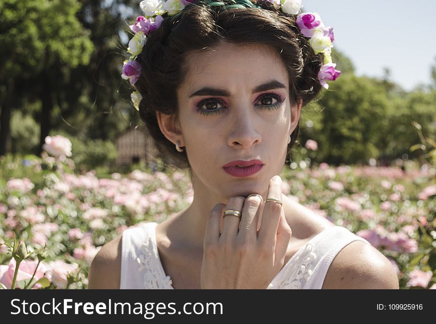 Woman in White Floral Headdress and White Sleeveless Top Behind Pink Flower Field at Daytime