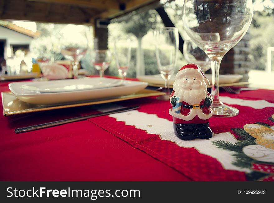 Santa Claus Ceramic Figurine Next to Wine Glasses and White Ceramic Plate