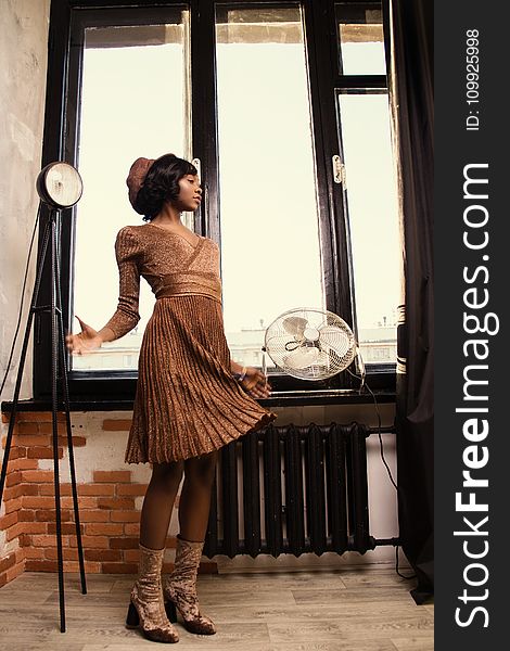 Woman In Brown Dress Standing Beside Black Desk